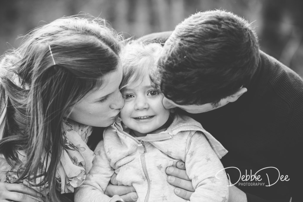 Family Maternity Photography Session Mum and Dad kissing little girl on the cheeks
